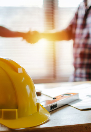 closeup of construction hat, handshake in the background